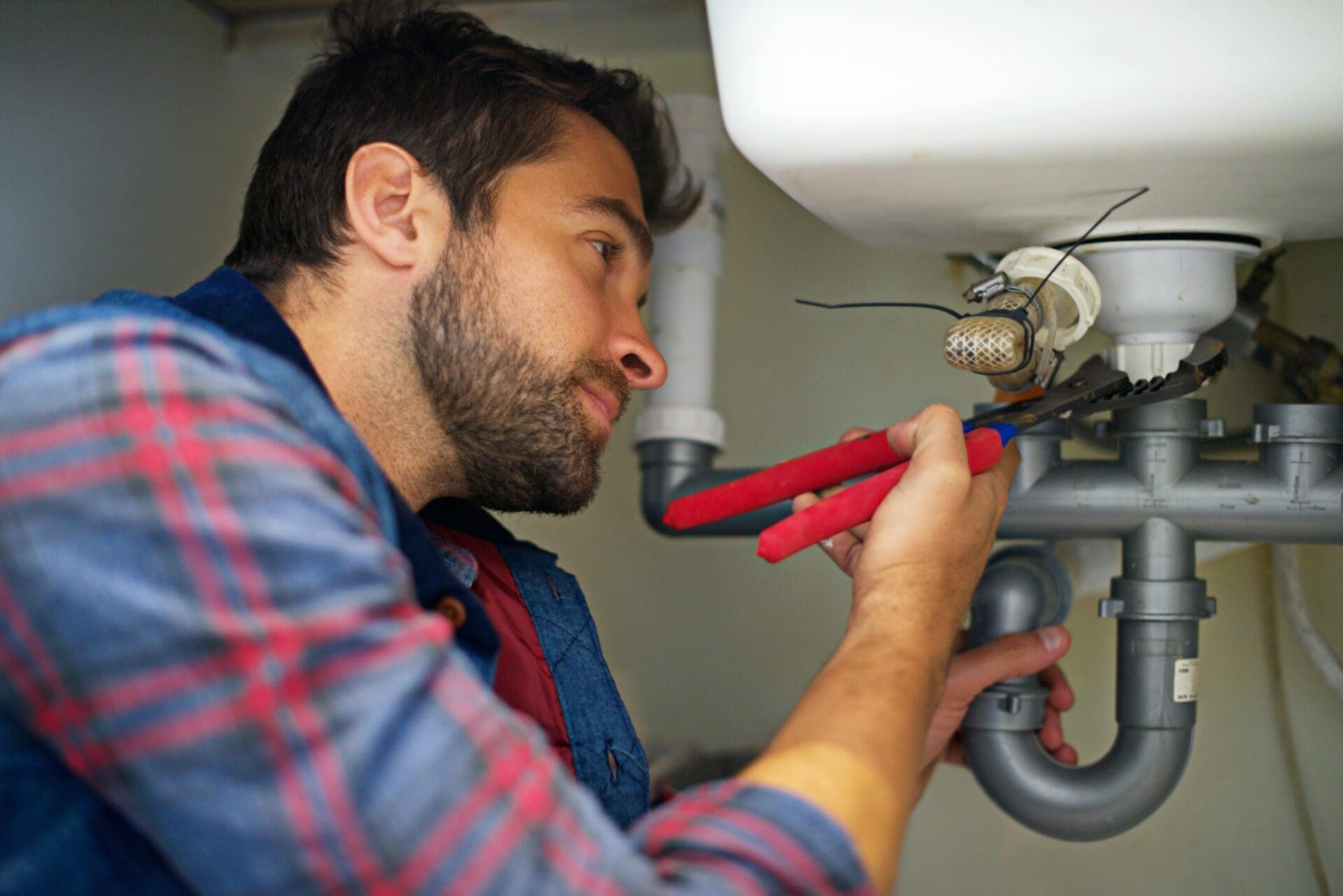 A man doing plumbing work with basic plumbing tools